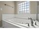 Relaxing bathroom featuring a jetted tub, tiled surround, and privacy window at 115 Blue Grass Way, Oxford, GA 30054