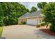 Side view of a home featuring an attached two-car garage and lush landscaping at 115 Blue Grass Way, Oxford, GA 30054