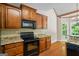 Well-lit kitchen with granite countertops, black appliances, and wooden cabinets at 115 Blue Grass Way, Oxford, GA 30054
