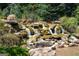 Beautiful rock waterfall feature with cascading water and lush greenery in a serene garden setting at 1516 Winward Dr, Locust Grove, GA 30248