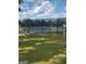 View of a fenced community tennis court with a green grass surround under a partially cloudy sky at 690 Gateway Ct, Stone Mountain, GA 30087