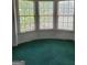 Green carpet and bare walls in a small room with a window, awaiting your personal touch at 690 Gateway Ct, Stone Mountain, GA 30087