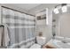 This bathroom features a shower with gray-and-white striped curtains, a toilet, and a white cabinet with storage space at 2006 Carrollton Hwy, Temple, GA 30179