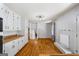 Open living room featuring a brick fireplace, hardwood floors, and white cabinets extending into the kitchen at 7121 Forest Se Dr, Covington, GA 30014