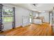 Open living room featuring a brick fireplace, hardwood floors, and white cabinets extending into the kitchen at 7121 Forest Se Dr, Covington, GA 30014