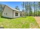 Exterior home view showcasing a white exterior, a covered patio, and a large backyard with trees at 1547 South Bethany Rd, Locust Grove, GA 30248