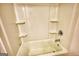A white shower and tub combo featuring built in shelving and chrome shower head and faucet at 2929 Rambler Dr, Loganville, GA 30052