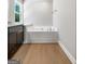 Bathroom showcasing a built-in soaking tub with a chrome faucet, dark cabinetry, and wood-look flooring at 1555 South Bethany Rd, Locust Grove, GA 30248