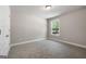 This bedroom has carpet flooring, neutral walls, white trim, and a window view of the greenery outside at 1555 South Bethany Rd, Locust Grove, GA 30248