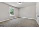 Bare bedroom featuring neutral colored walls, trim, and carpet along with a single window at 1555 South Bethany Rd, Locust Grove, GA 30248