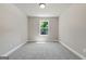 A simple bedroom with neutral-colored walls, trim, and carpet, and a single window for natural light at 1555 South Bethany Rd, Locust Grove, GA 30248