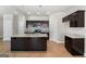 Open-concept kitchen boasts granite countertops, a kitchen island, dark cabinets, and stainless steel appliances at 1555 South Bethany Rd, Locust Grove, GA 30248