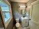 Small bathroom with oval mirror, vanity sink, toilet, and window at 1681 Stanton Sw Rd, Atlanta, GA 30311
