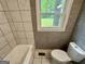 Bright bathroom with tiled walls, toilet, window, and modern vanity at 1681 Stanton Sw Rd, Atlanta, GA 30311