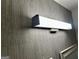 Close-up of a modern light fixture on the wall in bathroom with grey wallpaper at 1681 Stanton Sw Rd, Atlanta, GA 30311