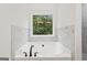 Soaking tub with picture window offering verdant views, along with marble tile at 2279 Lakeview Pkwy, Villa Rica, GA 30180