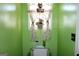 Bright bathroom with a toilet, window, patterned curtains, and cleaning supplies on top of the toilet at 239 Ferguson Ave, Locust Grove, GA 30248