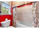 Bright bathroom with red accent wall, floral curtains, and a built-in tiled bathtub at 125 Lake Park Dr, Sharpsburg, GA 30277