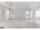 Bright bedroom with neutral carpet, ceiling fan, tray ceiling, and access to an ensuite bathroom at 125 Lake Park Dr, Sharpsburg, GA 30277