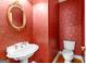 Charming powder room with red patterned wallpaper, decorative gold mirror and white pedestal sink at 125 Lake Park Dr, Sharpsburg, GA 30277