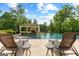 Backyard pool featuring lounge chairs, outdoor seating area with fireplace, and mature landscaping at 4320 Blue Ridge Dr, Douglasville, GA 30135