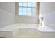 A bathtub has white tiling around the walls, a large window that lets in a lot of light, and chrome hardware at 10690 Tara Village Way, Joneboro, GA 30238