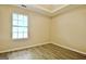 A bedroom has hardwood floors, neutral colored walls, a double hung window, and a tray ceiling at 10690 Tara Village Way, Joneboro, GA 30238