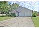 View of the gray home showing the driveway, lush lawn, and attached two-car garage at 10690 Tara Village Way, Joneboro, GA 30238