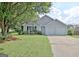 Charming gray home with a two-car garage, lush green lawn, and lovely landscaping at 10690 Tara Village Way, Joneboro, GA 30238