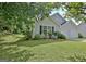 Landscaped front yard with lush green grass and mature trees surrounding the gray home at 10690 Tara Village Way, Joneboro, GA 30238