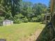 Spacious backyard with green grass, storage shed, and mature trees in a wooded setting at 212 Hunting Court, Jonesboro, GA 30236