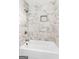 Beautiful white tub featuring gray and white marble-style tile, bronze fixtures and a recessed shelf at 317 Mcpherson Se Pl, Atlanta, GA 30316