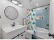 Bright bathroom featuring a tub/shower with stylish tile, vanity with sink, and dinosaur shower curtain at 11807 Alcovy Rd, Covington, GA 30014