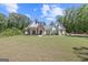 Charming white farmhouse-style home with a well-manicured lawn and inviting curb appeal surrounded by mature trees at 11807 Alcovy Rd, Covington, GA 30014