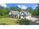 Beautiful white farmhouse with an attached garage, lush landscaping, and a welcoming front porch, nestled amongst mature trees at 11807 Alcovy Rd, Covington, GA 30014