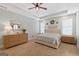 Neutral main bedroom with tray ceiling, ceiling fan, wood-look dresser, and light colored carpet at 11807 Alcovy Rd, Covington, GA 30014