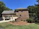 Rear view of a brick home with a three-car garage, lush lawn, and outdoor deck at 245 River Laurel Way, Woodstock, GA 30188