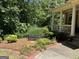 Landscaped flower bed with bench and columns of a brick home and covered front porch at 245 River Laurel Way, Woodstock, GA 30188