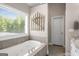 Relaxing bathroom featuring a soaking tub with tile surround and natural lighting at 692 Brooks Woolsey Rd, Brooks, GA 30205