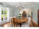 Open dining room with chandelier, wood floors, and natural light coming from a nearby window at 692 Brooks Woolsey Rd, Brooks, GA 30205