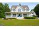 Charming two-story home with a wrap-around porch, manicured lawn, and mature landscaping at 692 Brooks Woolsey Rd, Brooks, GA 30205