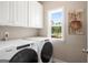 Bright laundry room with Whirlpool washer and dryer, white cabinets, and a window view at 692 Brooks Woolsey Rd, Brooks, GA 30205