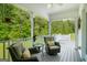 Relaxing covered porch with two chairs, a table, and view of a lush green forest at 692 Brooks Woolsey Rd, Brooks, GA 30205