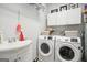 Bright laundry room featuring dual washer and dryer, sink, storage cabinets, and hanging rack at 960 Pebblestone Ct, Alpharetta, GA 30009