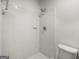 Clean and simple white tiled shower with shower head and toilet in renovated bathroom at 7455 Dover Ct, Riverdale, GA 30274