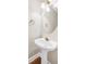 Powder room features a pedestal sink, round mirror, and wood-look flooring at 1315 Crane Ct, Mcdonough, GA 30252