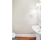 Powder room features a pedestal sink, round mirror, and wood-look flooring at 1315 Crane Ct, Mcdonough, GA 30252