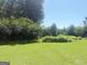 The landscaped backyard features green grass and privacy provided by mature trees and shrubs at 1869 Schofield Dr, Hampton, GA 30228
