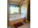 This bathroom features a soaking tub, neutral tile backsplash, with a bright window and tile floors at 1869 Schofield Dr, Hampton, GA 30228