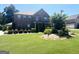 Charming two-story brick home with lush green lawn, mature trees, and colorful flower beds at 1869 Schofield Dr, Hampton, GA 30228